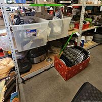 Overview of shelving with two slow cookers, storage bins, and a box of baking pans.