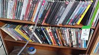 Photo of two shelves filled with assorted DVDs in cases, showing part of front and spine titles.
