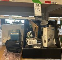 Photo showing multiple boxes of ink cartridges from Epson and HP, SanDisk hard drives, and other office electronics packed in a box.