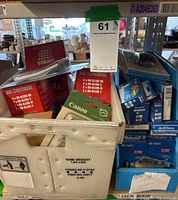 View of a white plastic bin on a shelf filled with various ink cartridges; visible red Brother LC65BULK boxes and small Canon cartridge