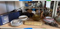 Wide view of all items on shelf showing bowls, plates, boxed stemware, and various glassware.