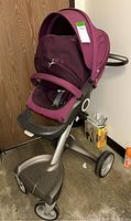 Side view of purple Stokke stroller showing frame, wheels, and canopy