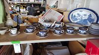 Overview photo of blue and white iron stoneware tea set including teapot, six teacups with matching saucers, plates stacked and oval serving platter