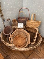 Image showing an assortment of different shaped and sized woven baskets assembled together, mainly wicker and natural fibers with various handles.