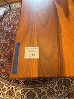 Close-up of tabletop showing wood grain and auction sticker #139