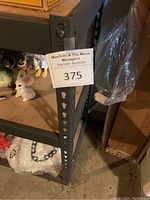 Corner close-up photo of the steel frame and MaxSold auction label 375 on shelf