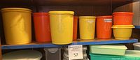 Front view of seven vintage Tupperware containers in yellow and orange on shelf