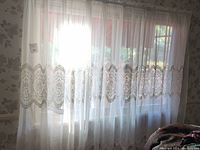 Full view of sheer curtains hung on rod showing white translucent fabric with central lace band across a window opening