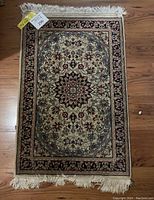 Full top-down view of the small area rug on wood floor showing entire rug and fringed edges