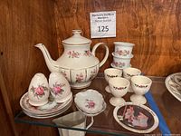 Full collection of mini flower pots, egg cups, butter plates, salt and pepper shakers, chocolate pot, saucers, and collector plate on the shelf.