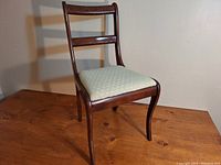 Front view of wooden dining chair with upholstered seat and curved backrest