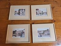 Four framed art prints laid out on wooden floor, showing village scenes by Alan Richardson