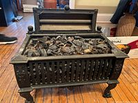 Antique cast iron electric fireplace with decorative glass rocks inside and opened top flap.