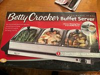 Photo of Betty Crocker Buffet Server packaging box showing product image and some specifications including 3 trays, 2.5 quart stainless steel trays with stainless steel frame, adjustable temperature, total capacity 7.5 quarts.