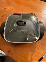 Black and Decker electric non-stick skillet with glass lid on wooden table