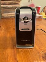 Front view of black and silver Hamilton Beach electric can opener showing latch and blade