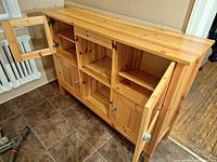 Front left angled view of kitchen sideboard showing open wood panel cabinet doors with shelves and center open shelving area with a drawer above.