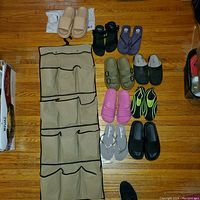 Nine pairs of ladies sandals and water shoes arranged on wooden floor including various colors and styles