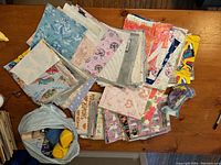 Photo showing a large assortment of wrapping paper sheets in different colors and patterns laid flat on a table.