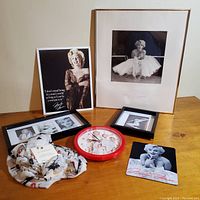 Overview of Marilyn Monroe collection including 5 pictures in frames, Marilyn Monroe clock with red frame, infinity scarf with Marilyn images, and a Marilyn Monroe themed item likely a placemat or coaster