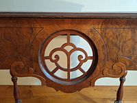 Close-up of the decorative circular wood carving on the front panel of the radio table, showing detailed scrollwork design.