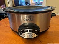 Front view of the Rival Crock-Pot with stainless steel body and control panel showing multiple buttons and settings.