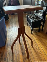 Side view of a small wooden side table showing square tabletop and four curved legs on pedestal base.
