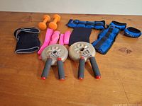 Top view of exercise weights and wrist bands on wooden surface showing all items in the lot