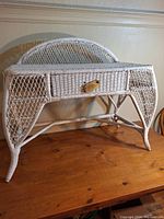 White wicker make up table front view showing single drawer with brass handle on wooden surface