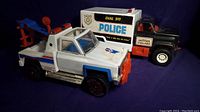 Metal tow truck and plastic police truck with visible wear and details