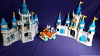 Photo showing two vintage plastic Mickey Mouse castles and a battery-operated car with Mickey and Donald figurines.