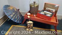 Photo showing wooden breakfast tray with ice container, boxed sushi set, Chinese dragon figurine, and decorative blue Chinese umbrella in the background.