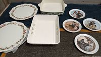 Full view of four Lenox holiday bakeware pieces and four Norman Rockwell 1982 collectible plates arranged together.