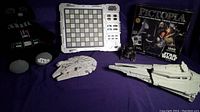 Photo showing Darth Vader plush teddy bear, electronic Galactic Chess Board without pieces, Star Wars Pictopia trivia game box, Millennium Falcon Micro Machine, Galactic Destroyer Micro Machine, and a small black droid figure.