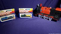 Lot shows two boxed diecast metal N gauge locomotives and tenders alongside a large red and black battery operated toy train engine.