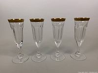 Four crystal champagne flutes standing side by side against a neutral background