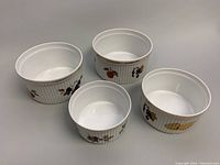 Top down view showing all four white porcelain soufflé dishes with Evesham fruit pattern, arranged slightly spaced on flat surface.