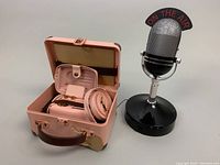 AM/FM Windsor Microphone MR-7 novelty transistor radio next to open pink suitcase-style case with MUZEN MW-2A1 portable FM radio, straps, and cables