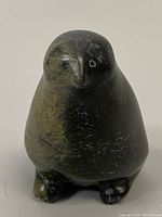Front view of the vintage Inuit signed penguin soapstone carving showing its dark stone color and signs of wear including nicks and surface scratches.