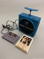 Square blue Panasonic RQ-830S 8-track player with power cord, SNES Royal Rumble cartridge, and Johnny Cash 8-track tape