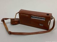 Side view of brown leather carrying case with strap and snap closure.