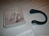 Photo of dark green bladeless neck cooler placed next to its retail box showing product shape and condition.