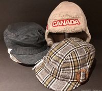 Three hats arranged in a group: Hudson Bay Canada Olympic Trapper Hat aviator style, Barts Tweed Cap, and Smartwool Cap.