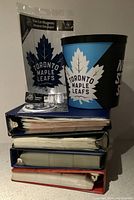 Photo of Toronto Maple Leafs ice bucket, coasters, magnet on top of hockey card binders showing the lot contents.