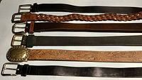 Seven women's medium leather belts laid flat showing color, texture, and buckle styles including braided and embossed designs.