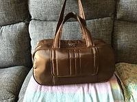 Side view of the brown Lug travel bag showing shape and padded carrying handles.