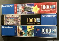 Three boxed Ravensburger 1000 piece puzzles stacked, showing brand, piece count, and part numbers.