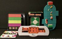 Lot of four sliding puzzles arranged in one photo showing Rudenko's Mosaic, Flip Side, Port to Port, and Magic Snake boxed puzzle.