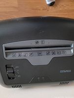 Top view of Staples paper shredder control panel showing paper feed slot, switch, and icons