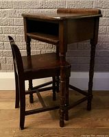 Side angled view of vintage wooden telephone table and chair showing turned legs and overall shape.